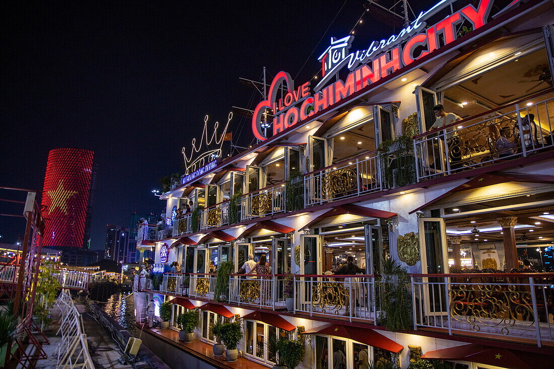 Das beleuchtete Dinner-Ausflugsboot Indochine nähert sich nachts dem Pier am Saigon-Fluss, Ho-Chi-Minh-Stadt, Vietnam, Asien