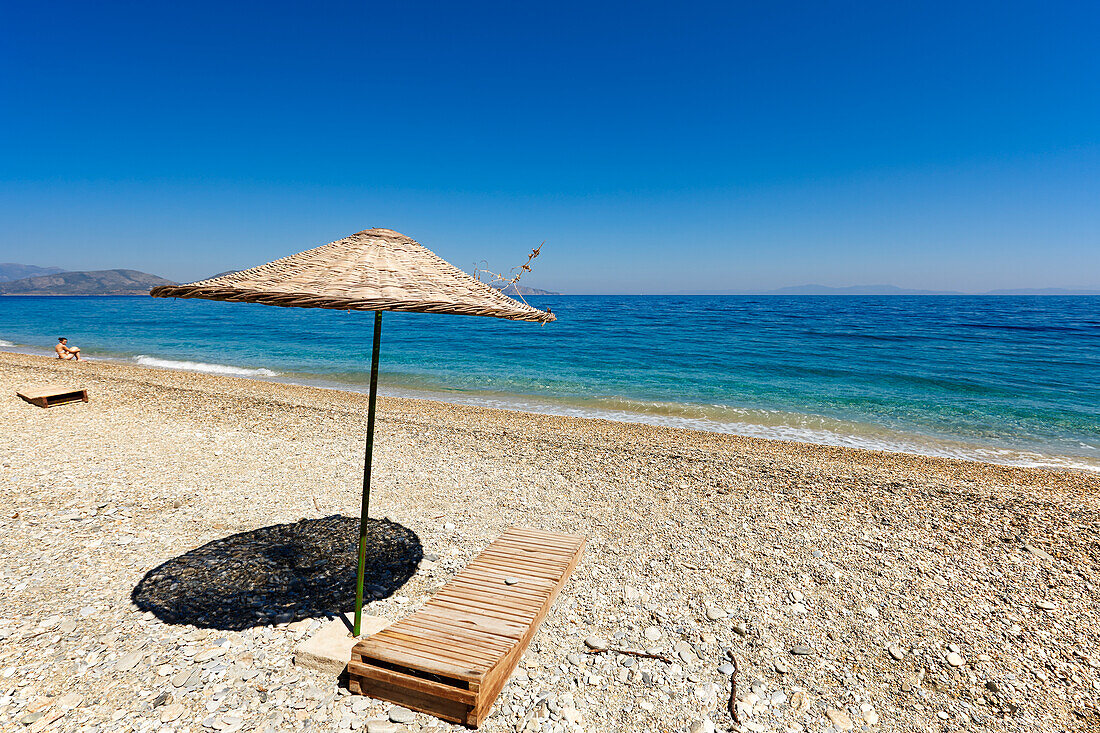 Sunbed under parasol on a pebble beach at Dilek Peninsula National Park, Aydin Province, Turkey.