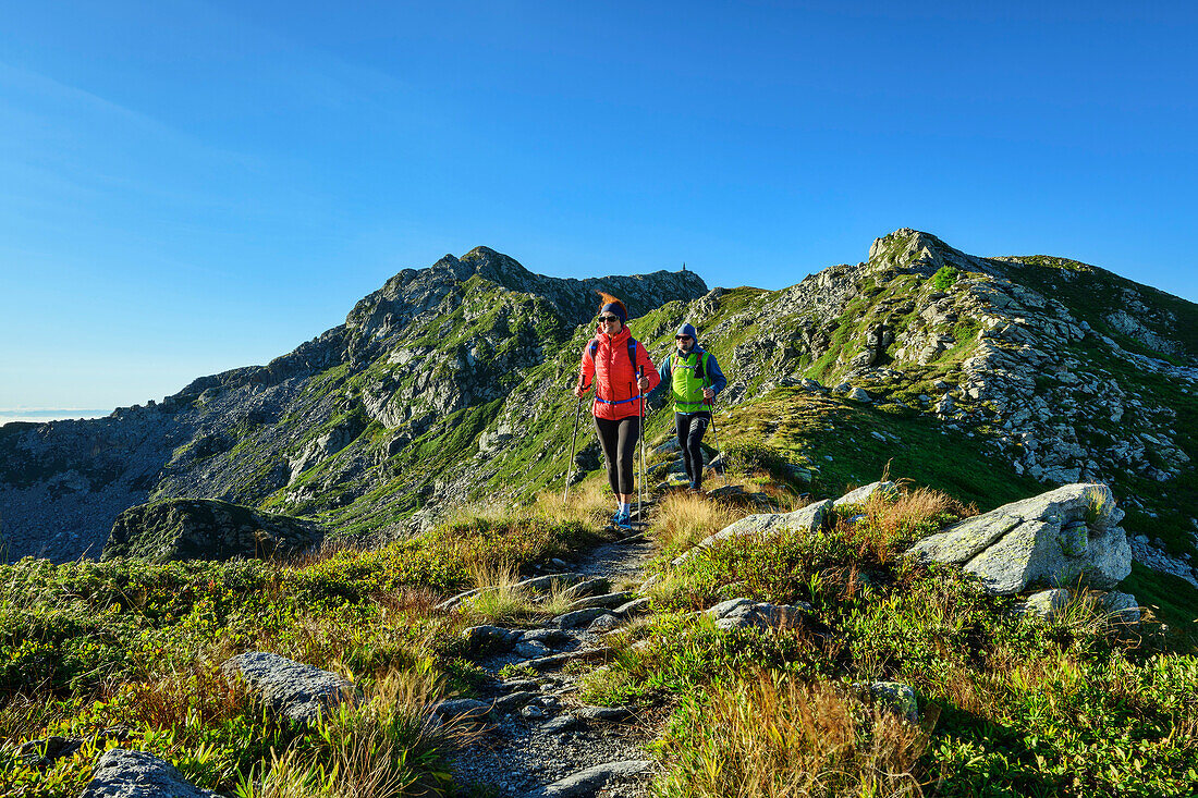 Mann und Frau wandern auf der GTA mit Mombarone im Hintergrund, Colma di Mombarone, GTA, Grande Traversée des Alpes, Biella, Alpi Biellesi, Walliser Alpen, Piemont, Italien