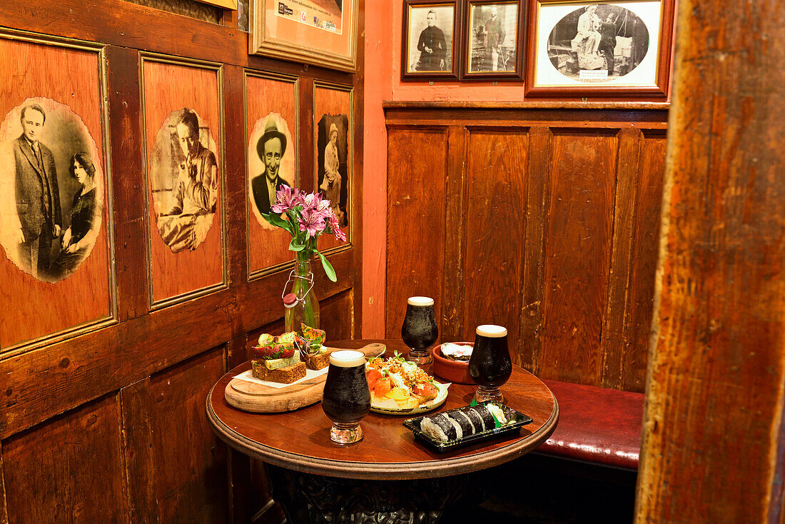 Sitzecke mit Essen und Guiness Bier im historischen Pub 'Tigh Neachtain', Cross Street, Galway, Connemara, County Galway, Republik Irland, Nordwesteuropa