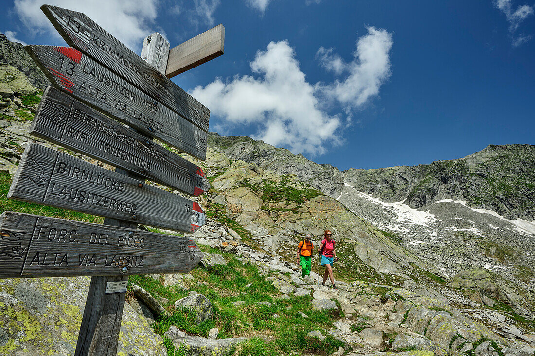 Mann und Frau beim Wandern mit Wegweiser im Vordergrund, Ahrntal, Lausitzer Weg, Zillertaler Alpen, Südtirol, Italien