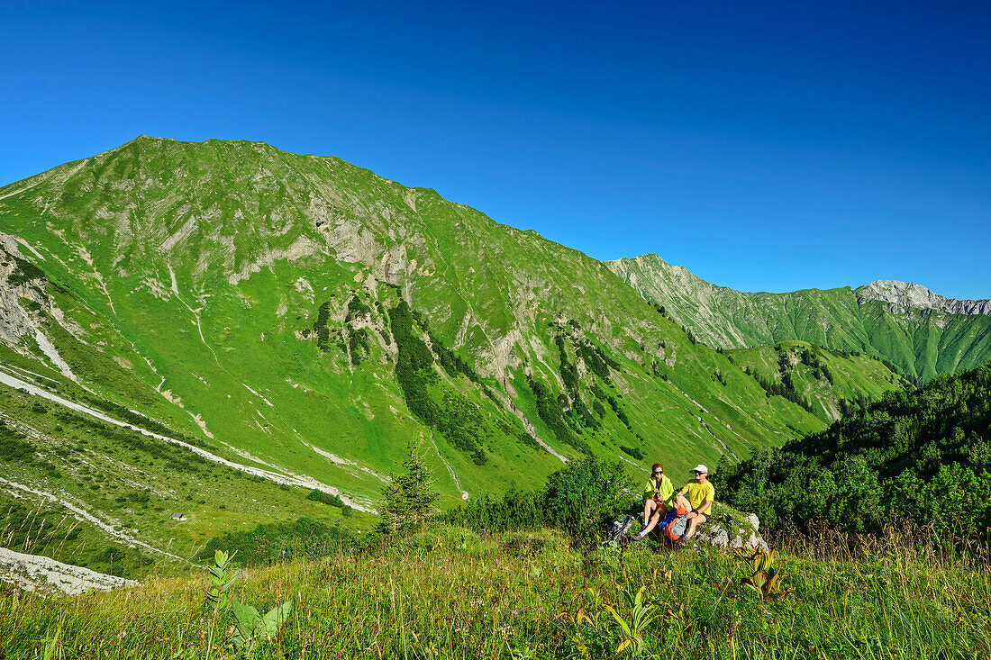 Mann und Frau beim Wandern sitzen auf Felsen und machen Pause, Namloser Wetterspitze, Lechtaler Alpen, Tirol, Österreich