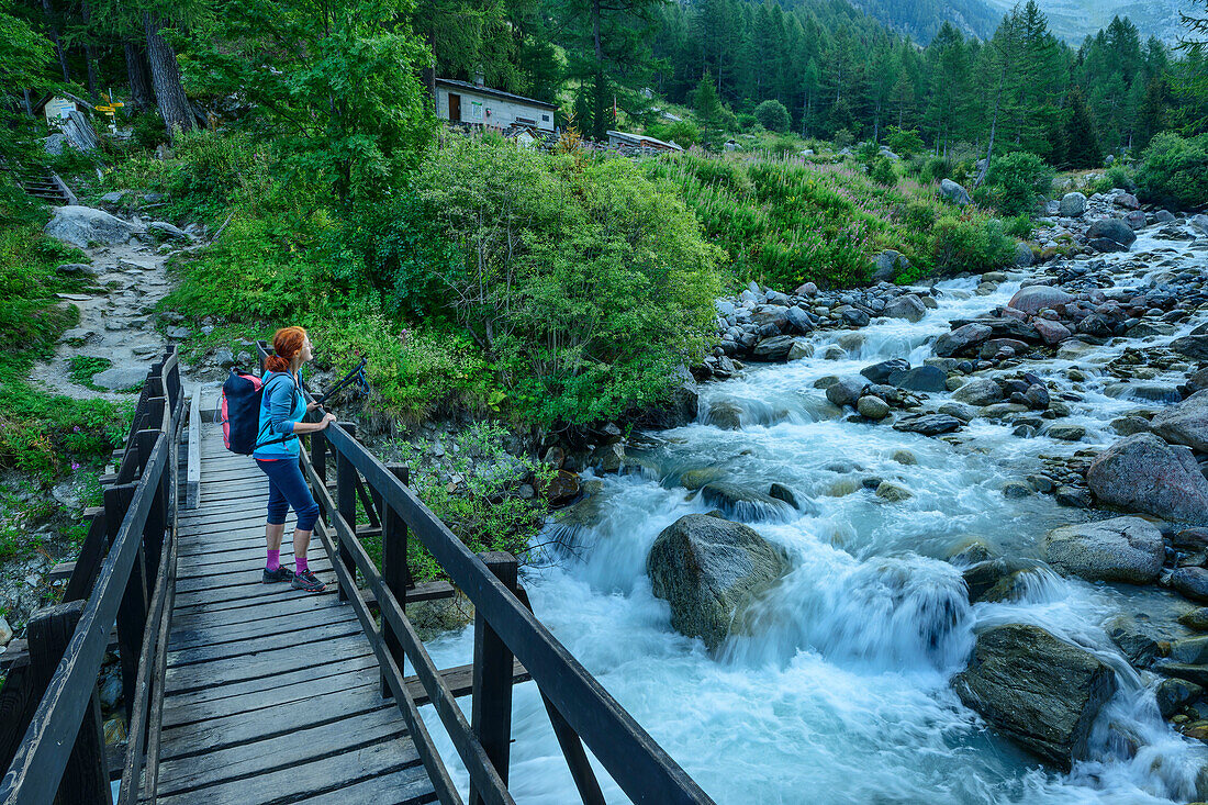 Frau beim Wandern überquert Fluss Trient auf Holzbrücke, Tour du Mont Blanc, Mont-Blanc-Gruppe, Grajische Alpen, Wallis, Schweiz