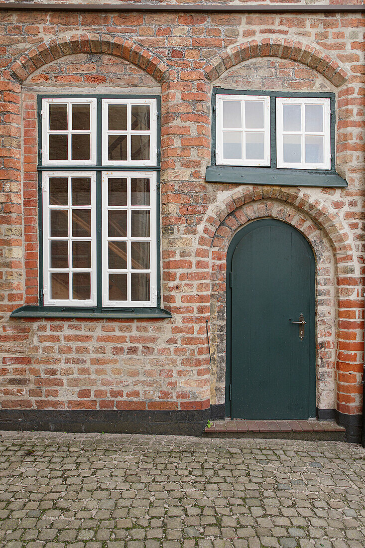  Green front door and lattice windows on brick facade 