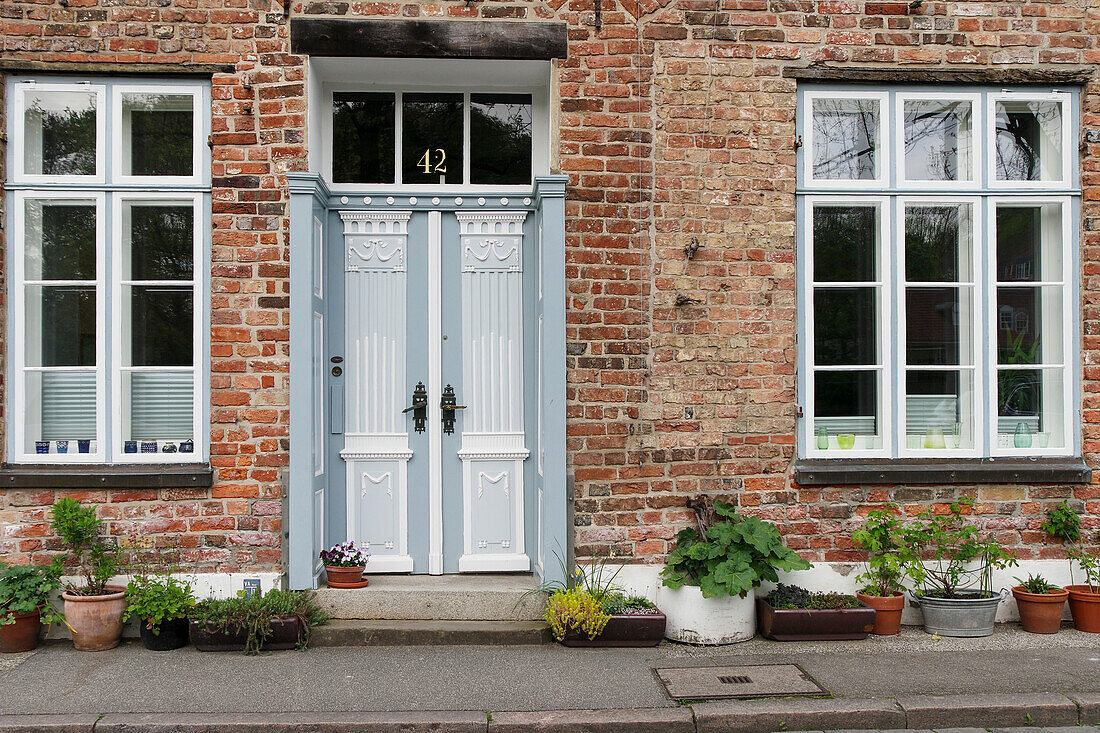  Grey-white old front door and lattice windows and plant pots on old house 