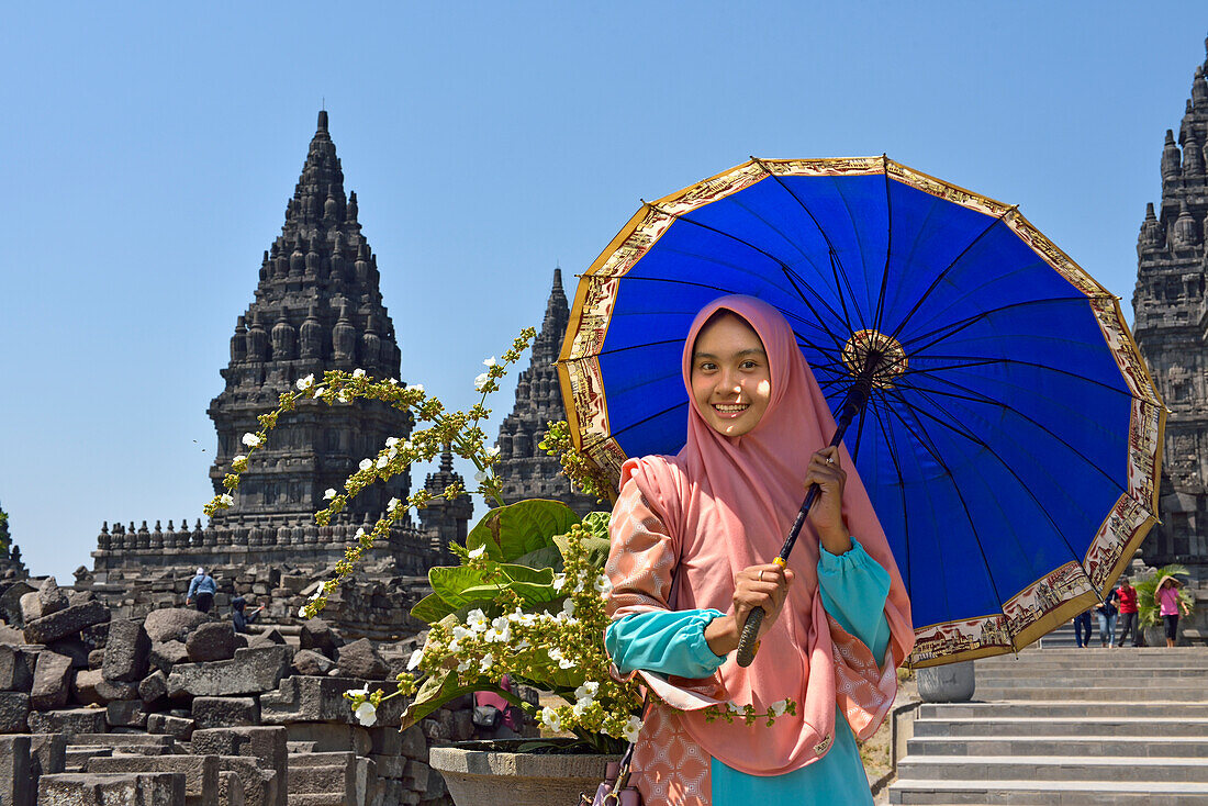 Junge Frau mit Sonnenschirm posiert auf dem Prambanan-Tempelgelände, Region Yogyakarta, Insel Java, Indonesien, Südostasien