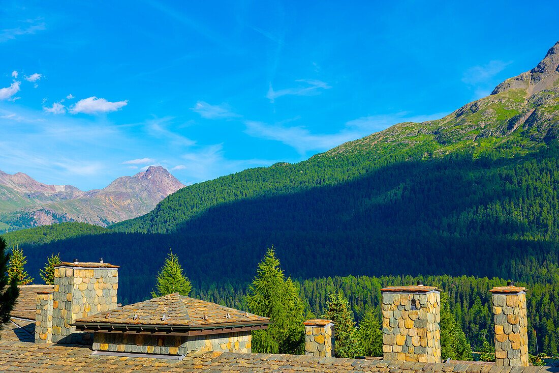 Rooftop with Chimney and Mountain Range and Blue Sky with Clouds in a Sunny Summer Day in Engadine, Maloja, Grisons, St Moritz, Switzerland.