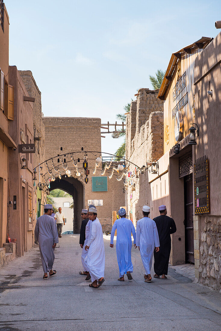 Gruppe junger Männer in einer Straße in der Altstadt von Nizwa, Ad-Dakhiliyah Region, Sultanat Oman, Arabische Halbinsel, Naher Osten