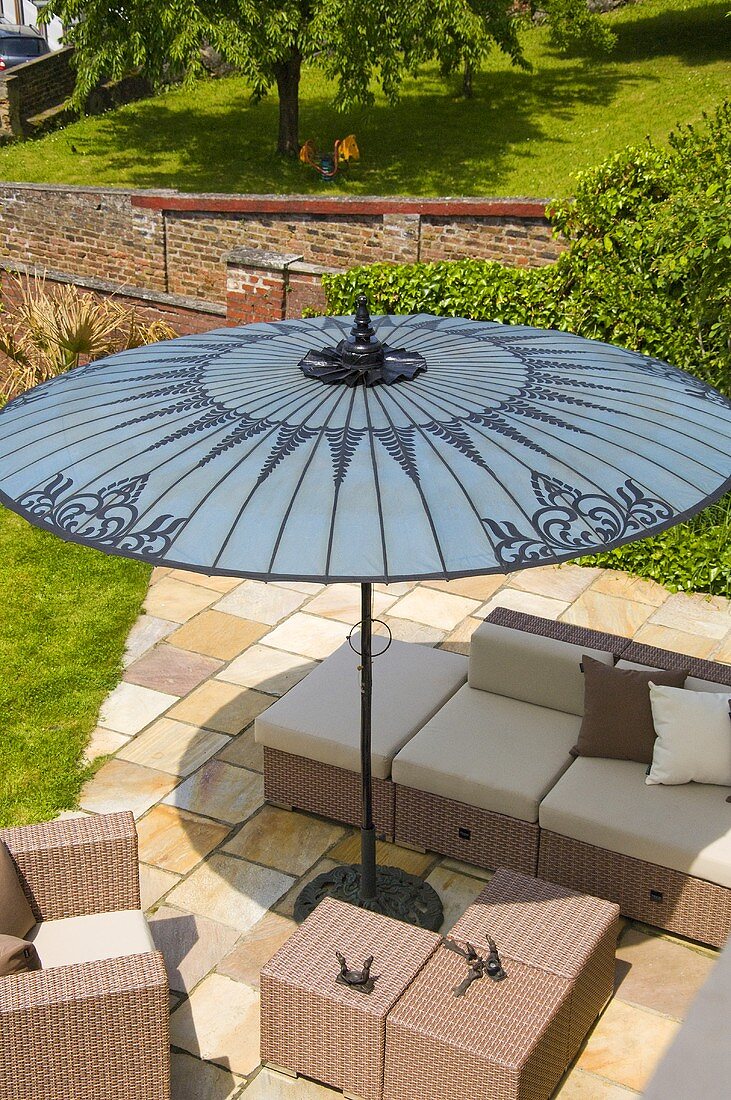 Wicker furniture on a terrace under a grey sunshade