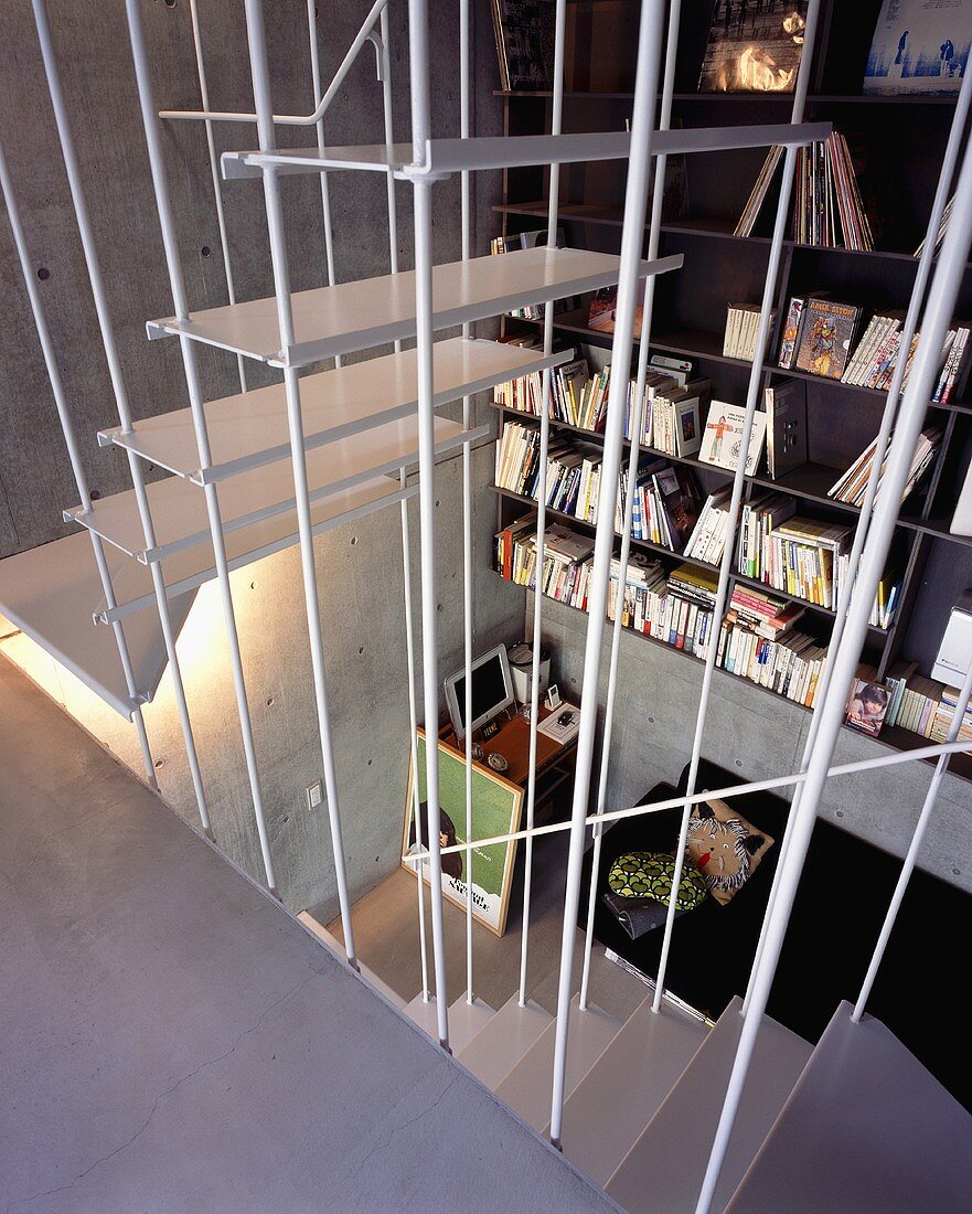 An open stairway with a view of a shelf in front of a concrete wall