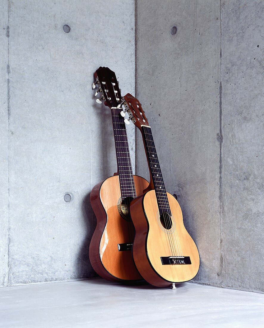 Guitars in a corner of a room with a concrete wall