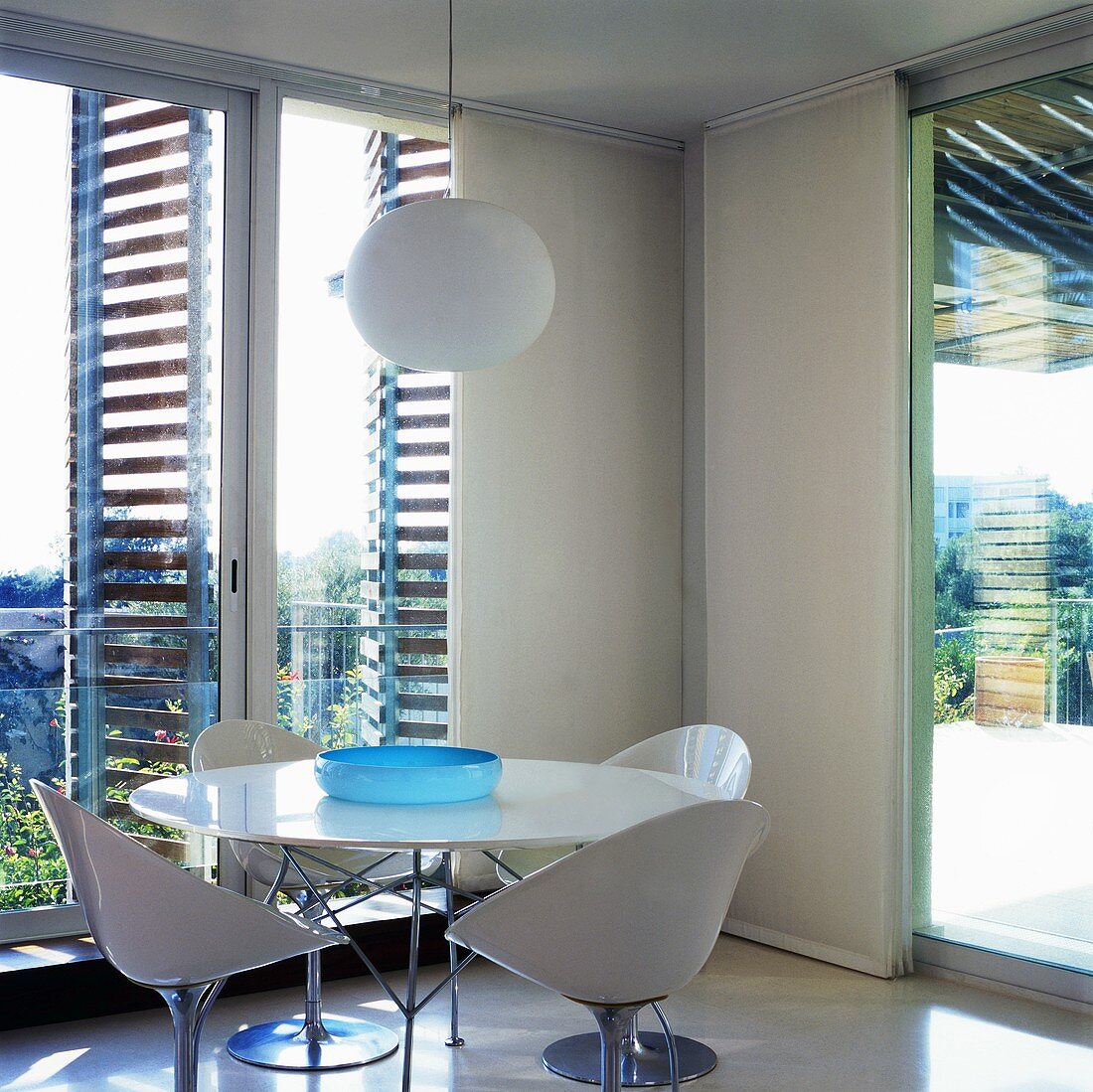 A table with white plastic bucket chairs and a designer pendent lamp