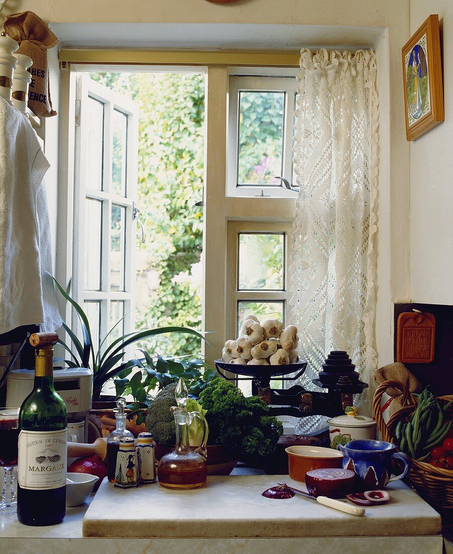 Eine Marmorplatte mit Zwiebel und Öl vor dem Küchenfenster mit weißem Spitzenvorhang