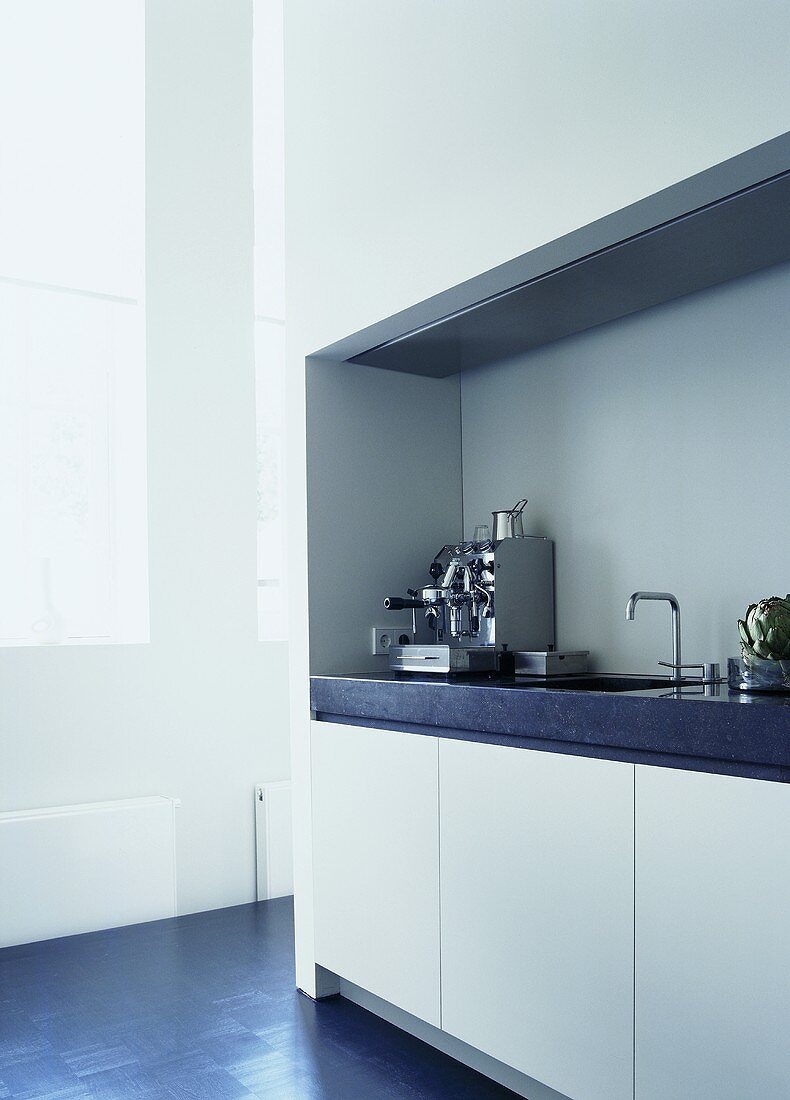 A white fitted kitchen with a work surface made of Belgian granite