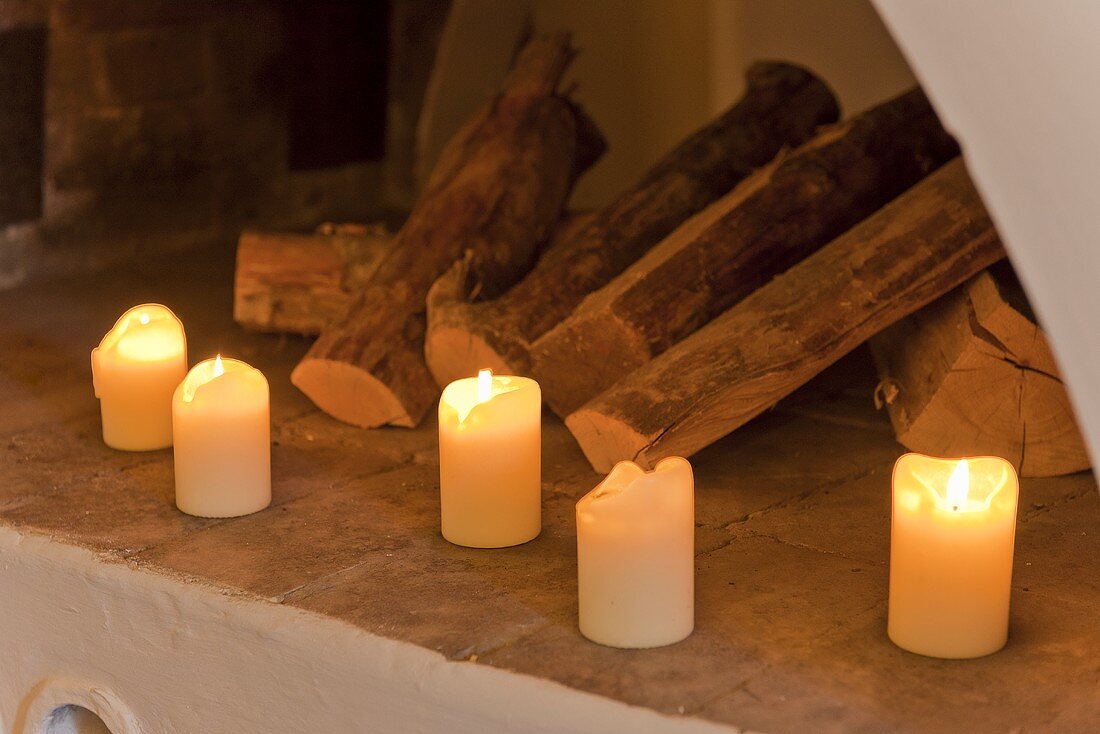 Burning candles and logs in front of a fireplace