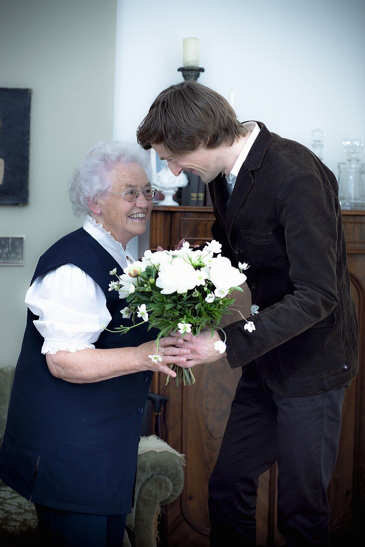 Enkel überreicht Grossmutter Blumenstrauss zum Geburtstag