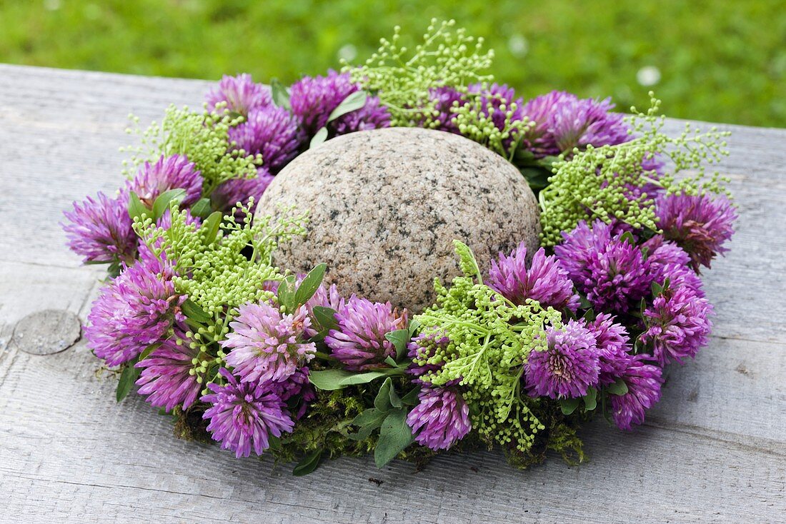 A wreath of clover flowers with green elderberries and a stone