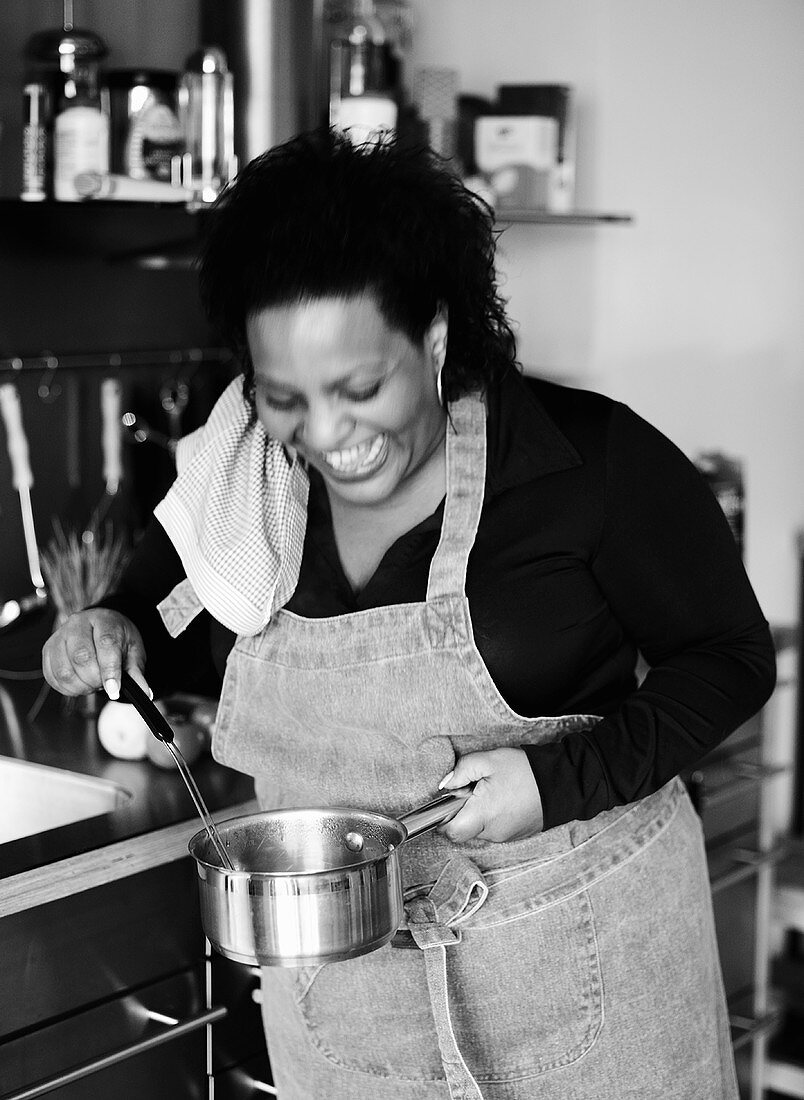 Laughing woman stirring a pan