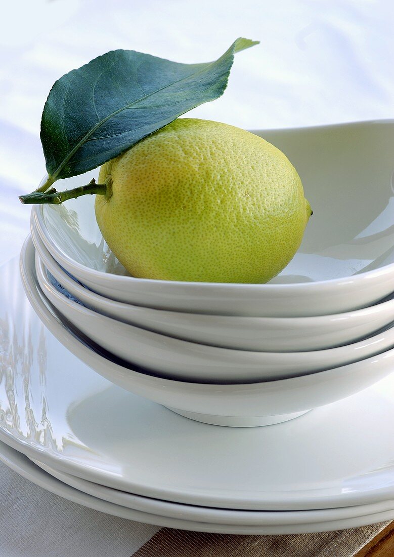 Lemon with leaf in stacked white bowls