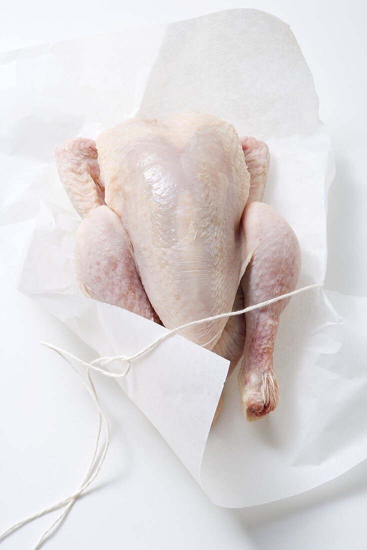A whole chicken with paper and string