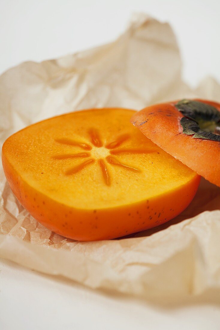 Persimmon with a slice removed on paper