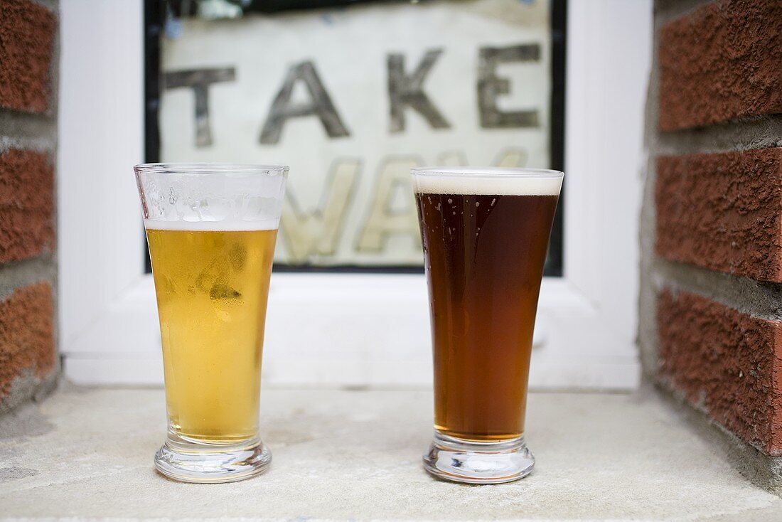 Two glasses of beer in front of Take Away sign