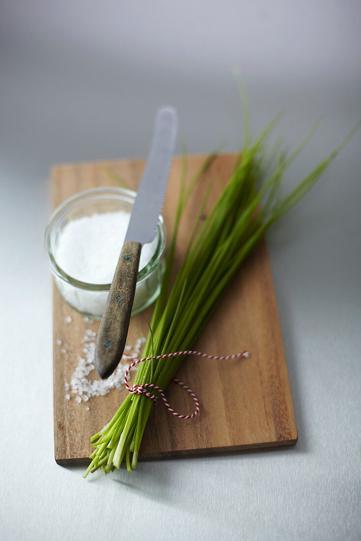 Sea salt in a bowl with a knife and chives