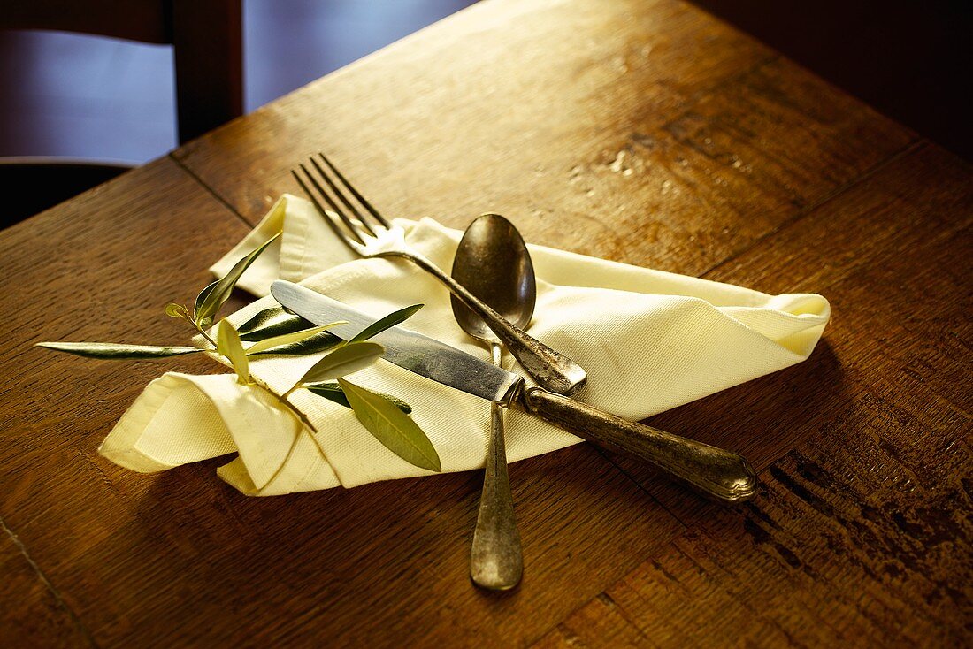 Cutlery on a serviette with an olive sprig