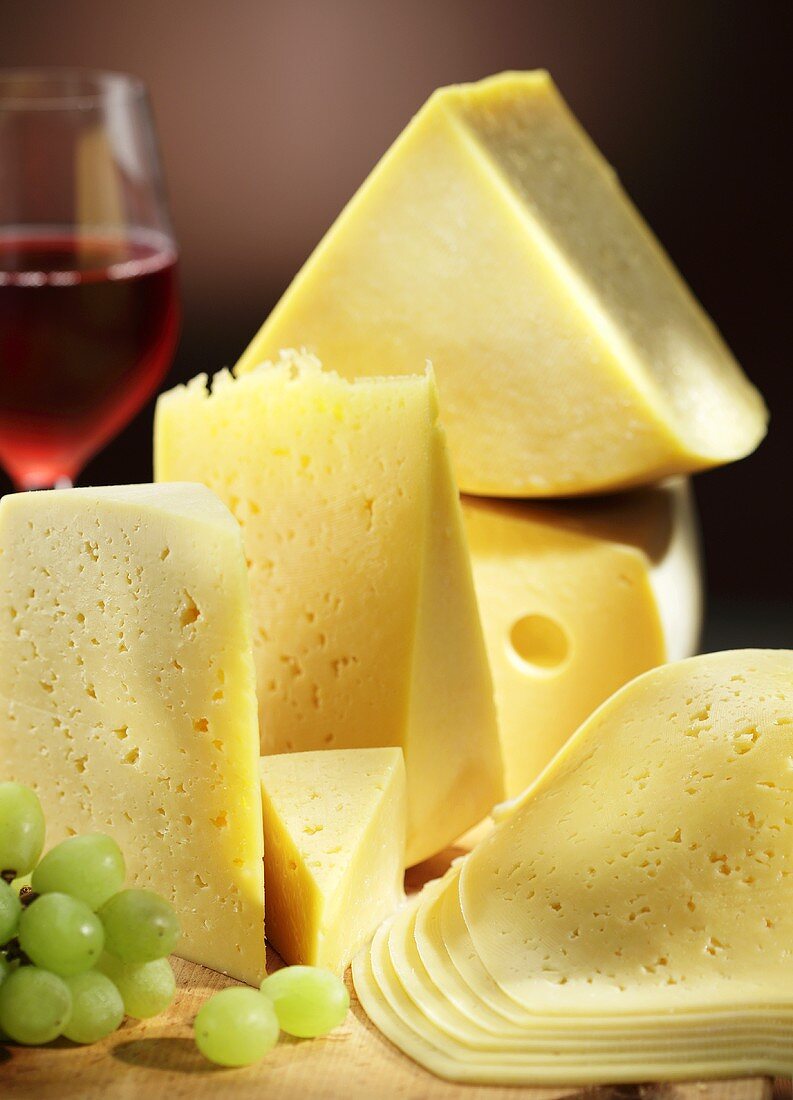 Various types of cheese with grapes and a glass of red wine