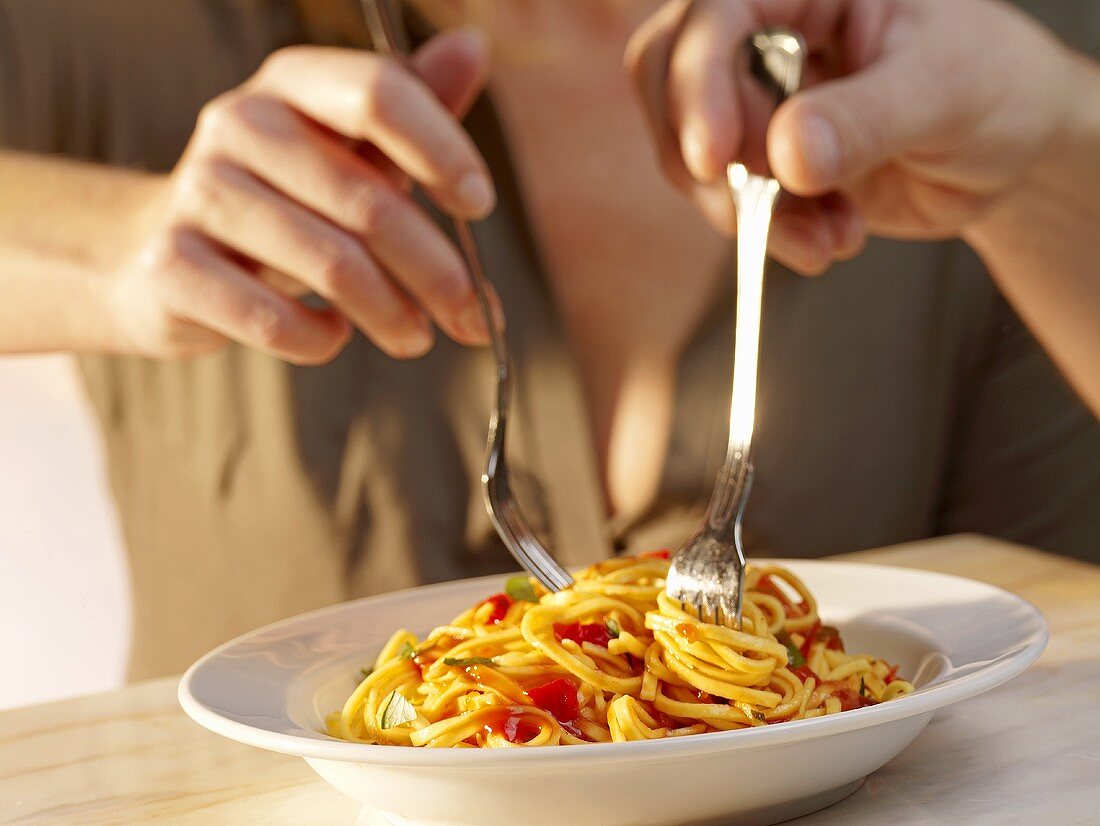 A man and a woman eating spaghetti