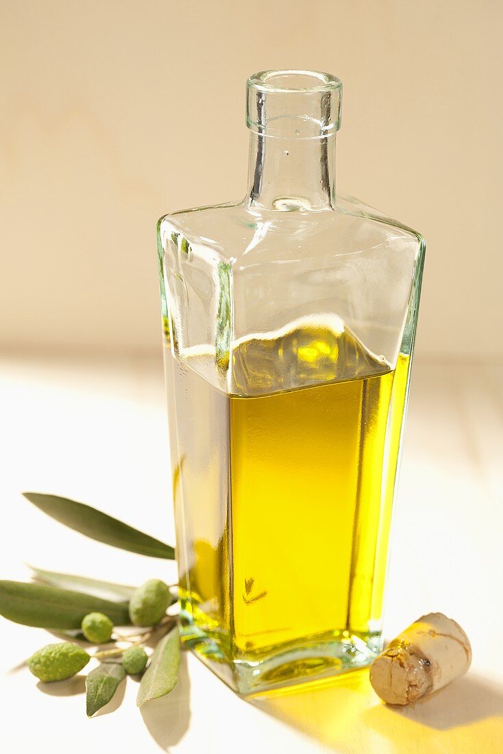 A bottle of olive oil with an olive twig