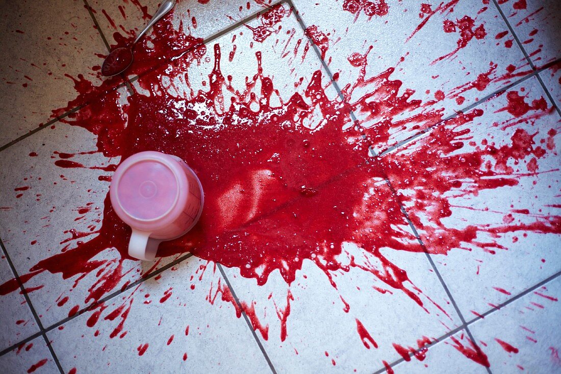 A measuring jug of strawberry puree spilt on the kitchen floor