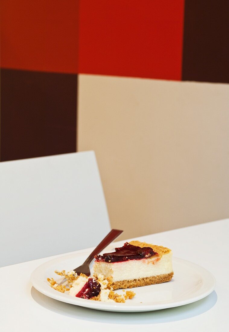 A piece of cheesecake with cherries on a plate with a fork
