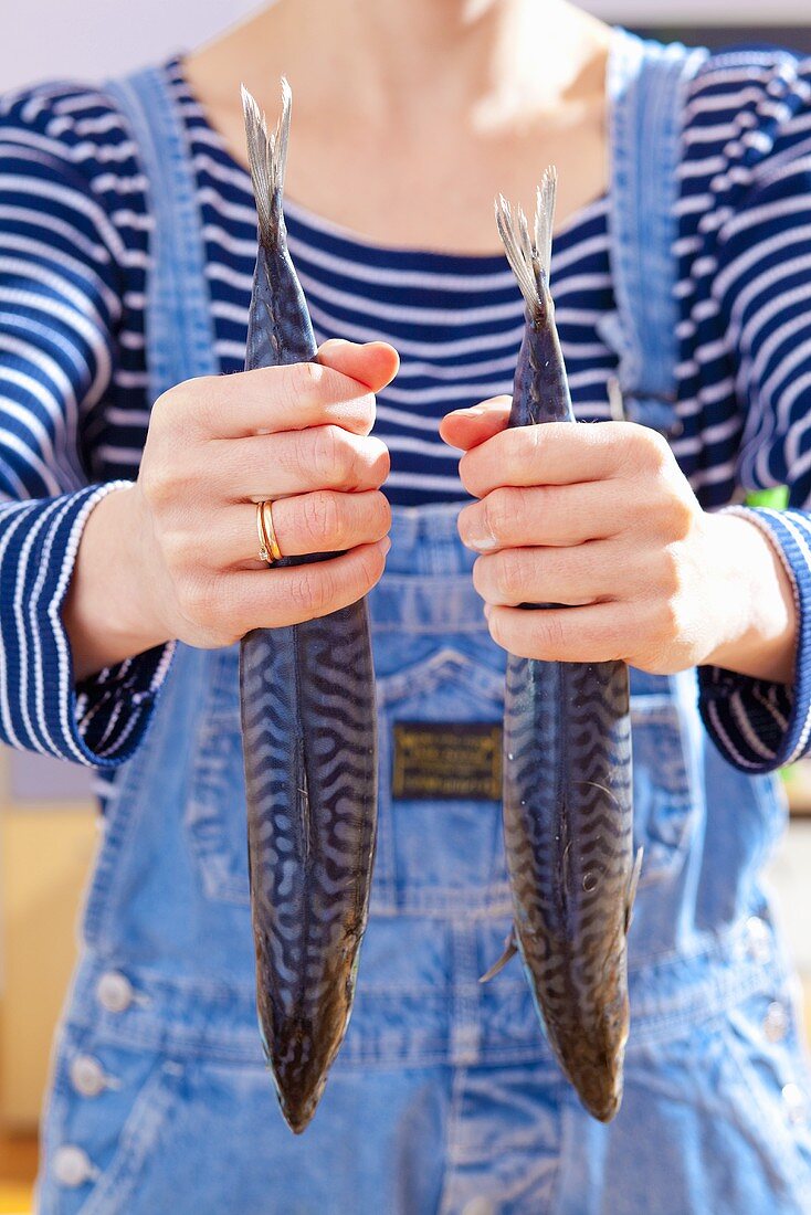 A woman holding two mackerel