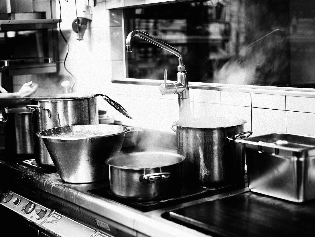 Dampfende Kochtöpfe in Restaurantküche