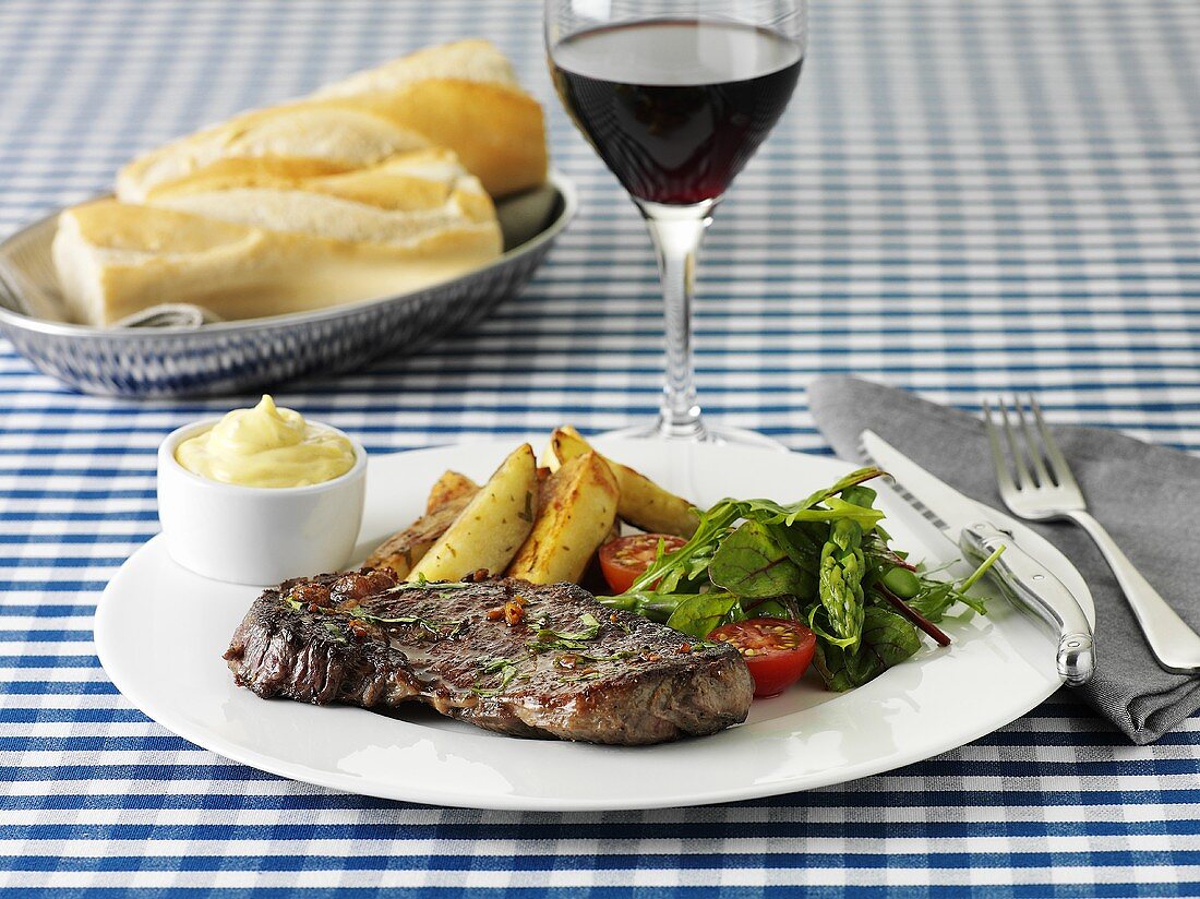 Beef steak with chips, salad and mayonnaise and a glass of red wine