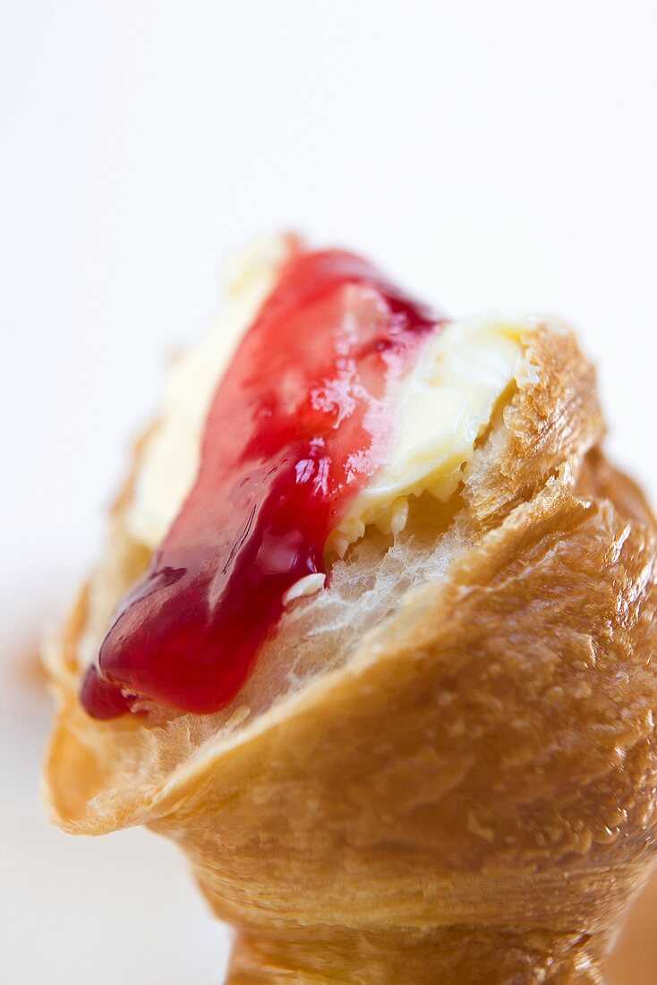 Croissant mit Butter und Erdbeermarmelade (Nahaufnahme)