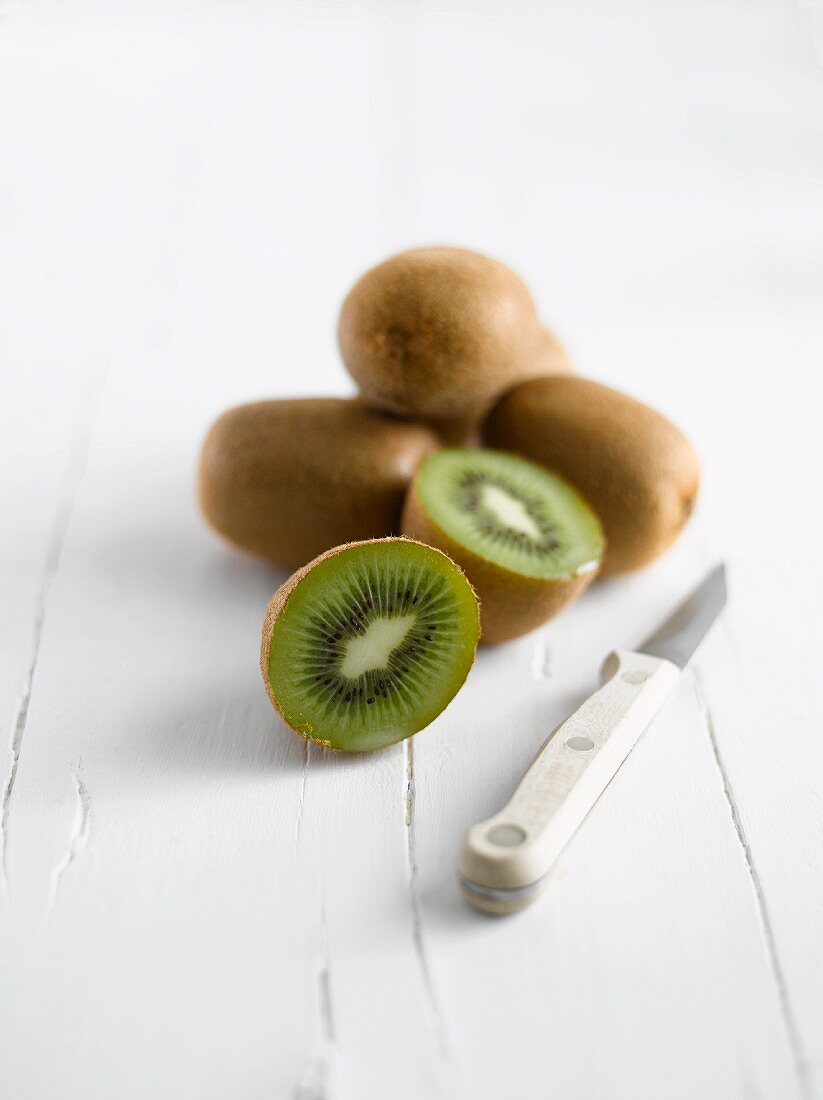 Kiwis, ganz und halbiert, mit Messer