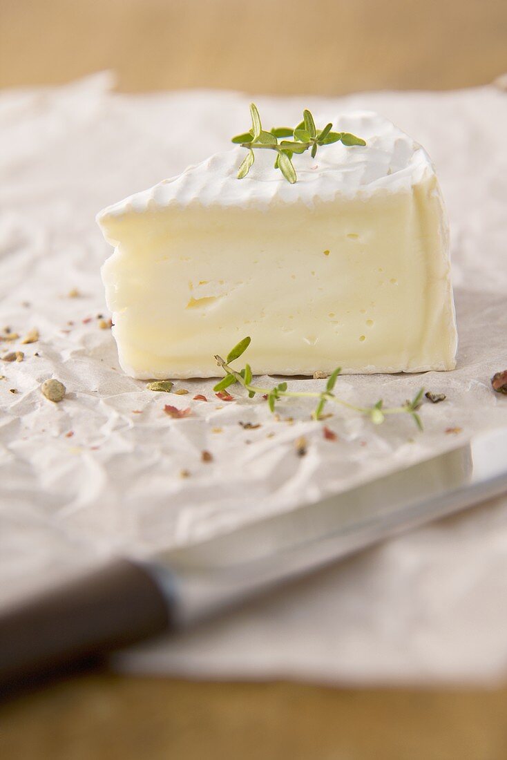 A piece of camembert with thyme and pepper
