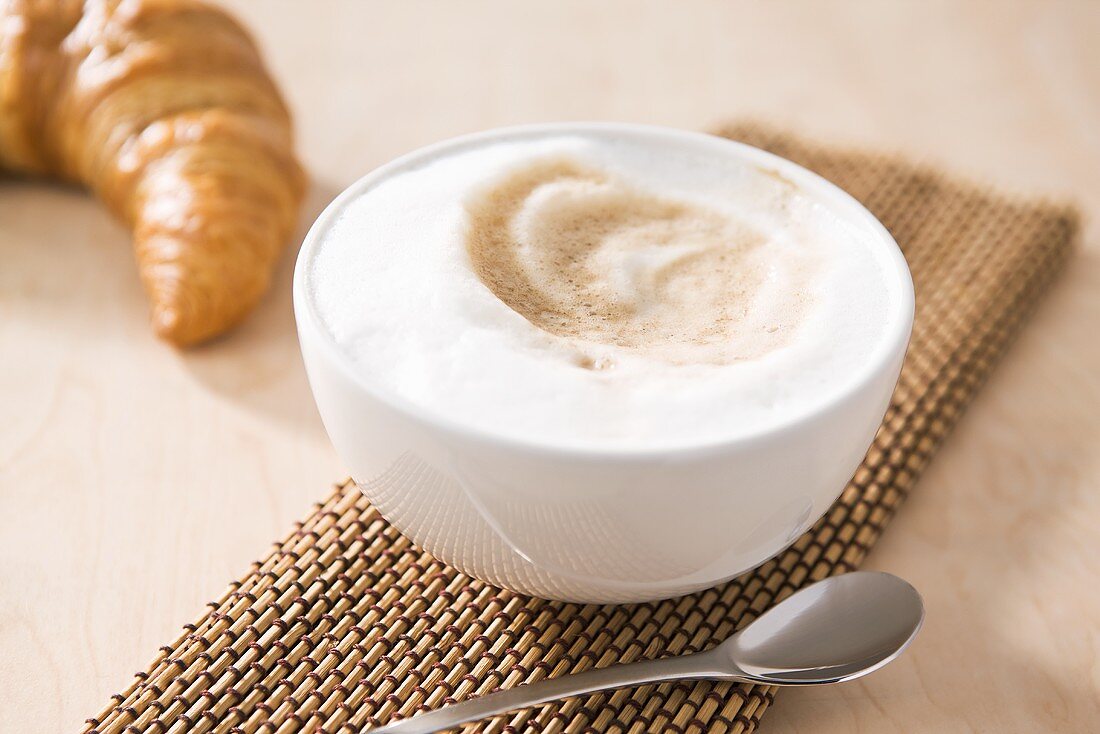 Kaffee mit Milchschaum und ein Croissant