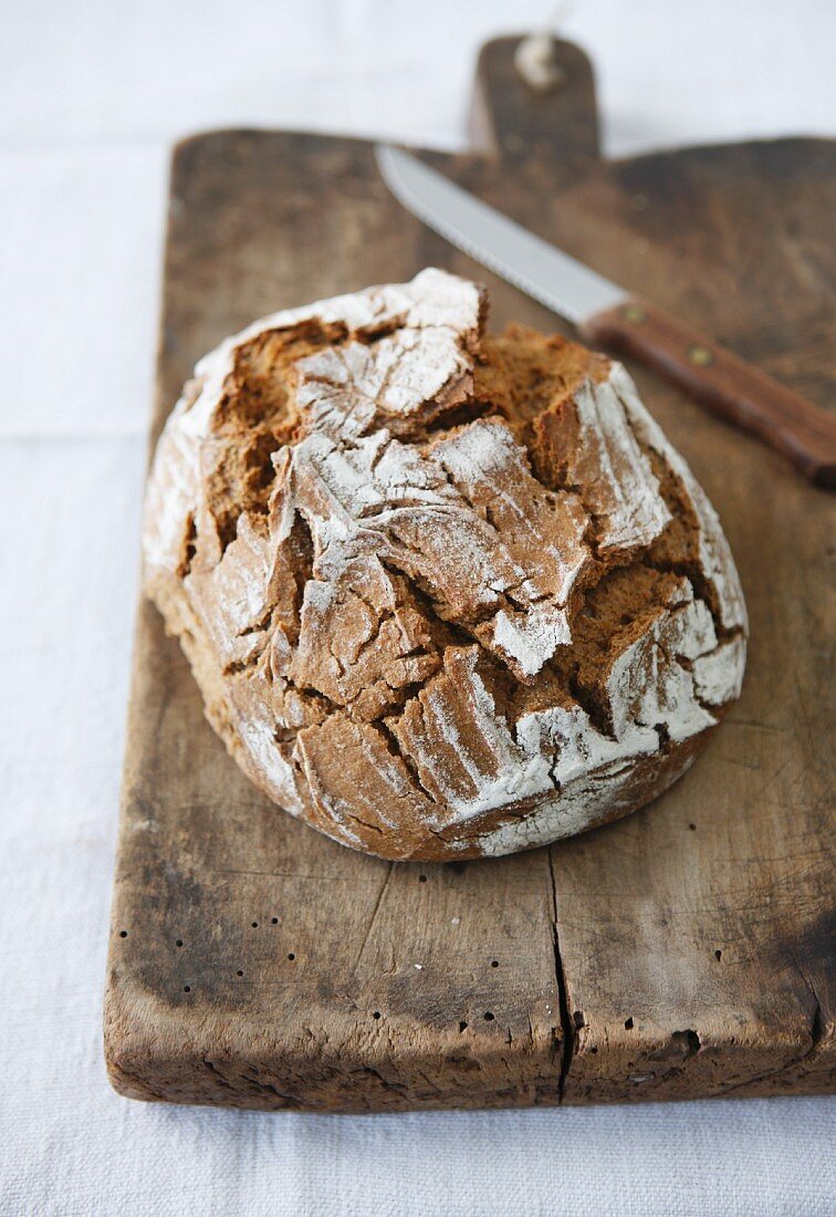 Rustikales Brot auf Schneidebrett mit Messer