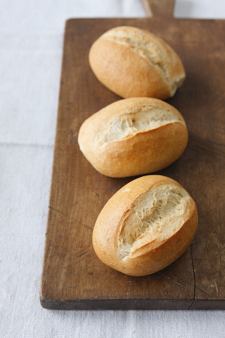Three bread rolls on a chopping board
