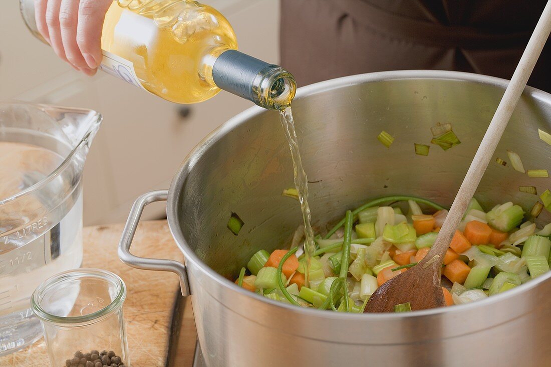 Pouring white wine into vegetables