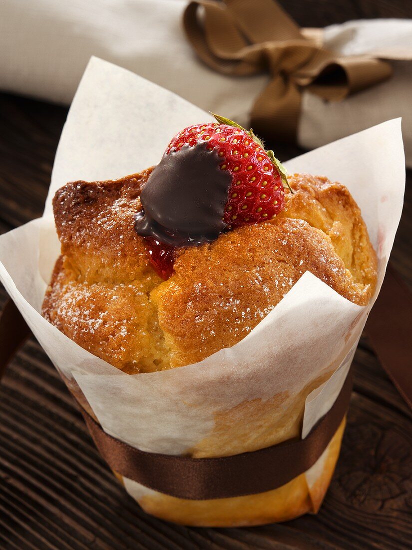 A strawberry muffin with a brown satin ribbon