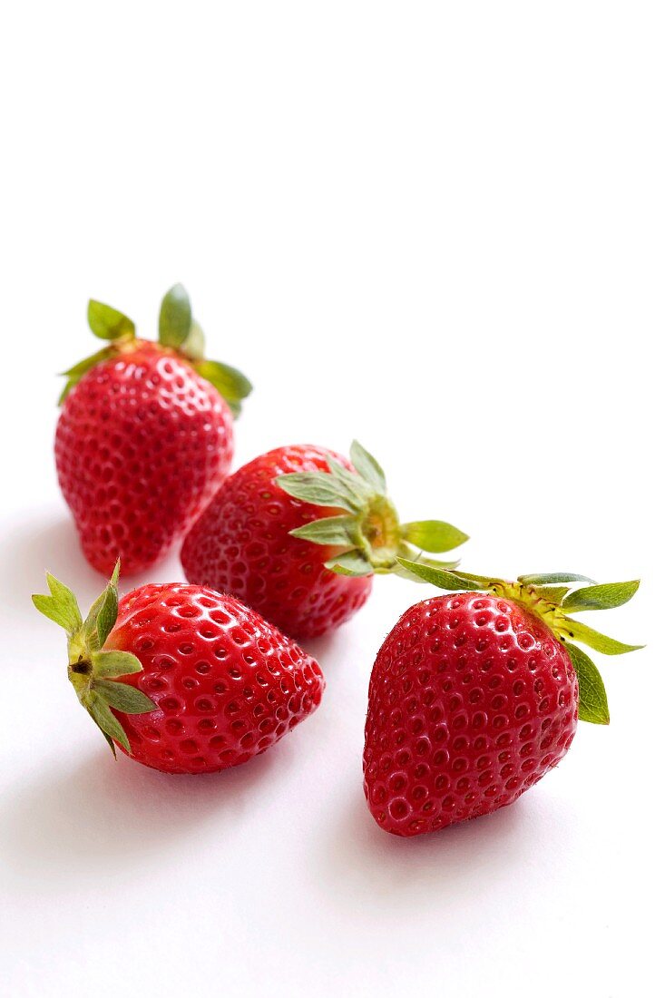 Five strawberries on a white surface