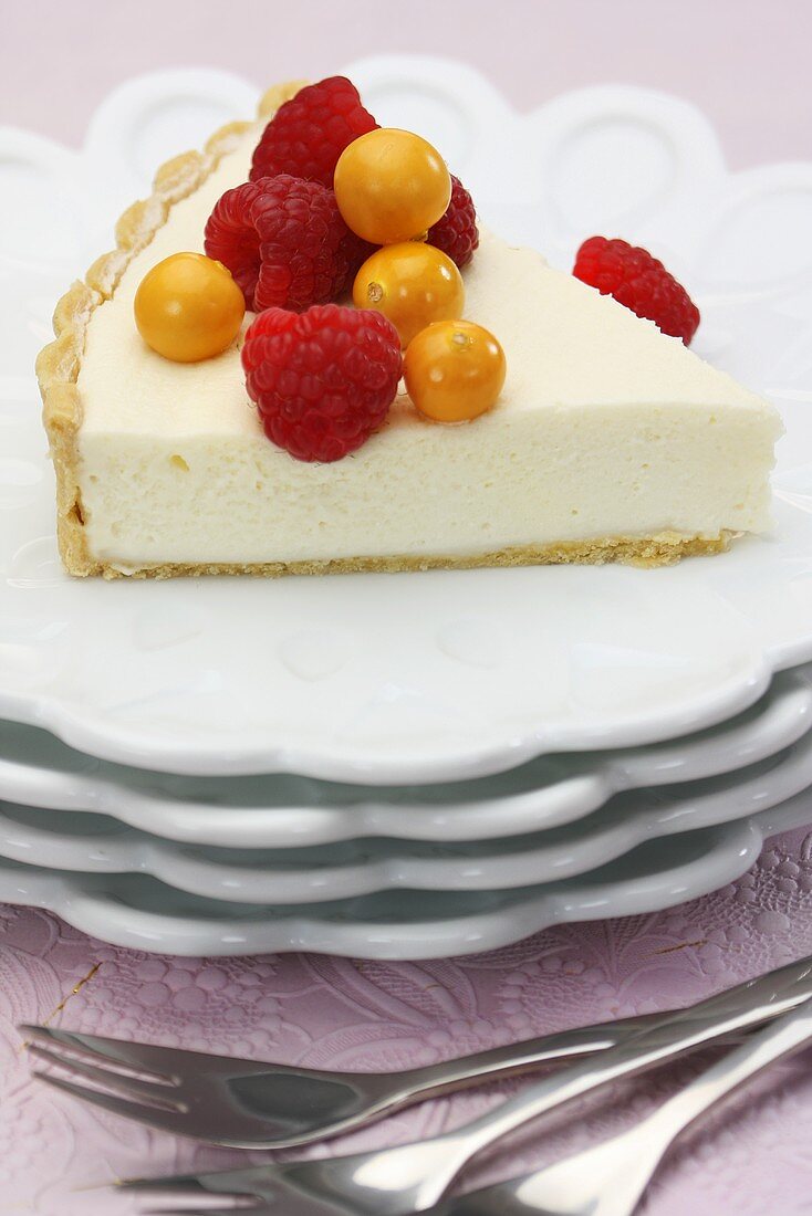 A slice of vanilla tart with cape gooseberries and raspberries