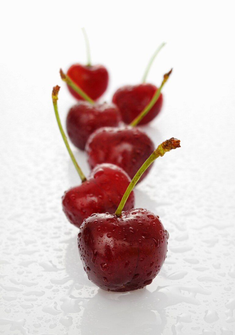 A row of cherries with water drops