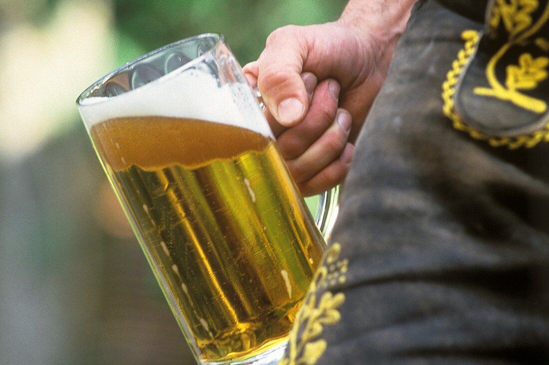 Eine Maß Bier an Lederhose gestützt