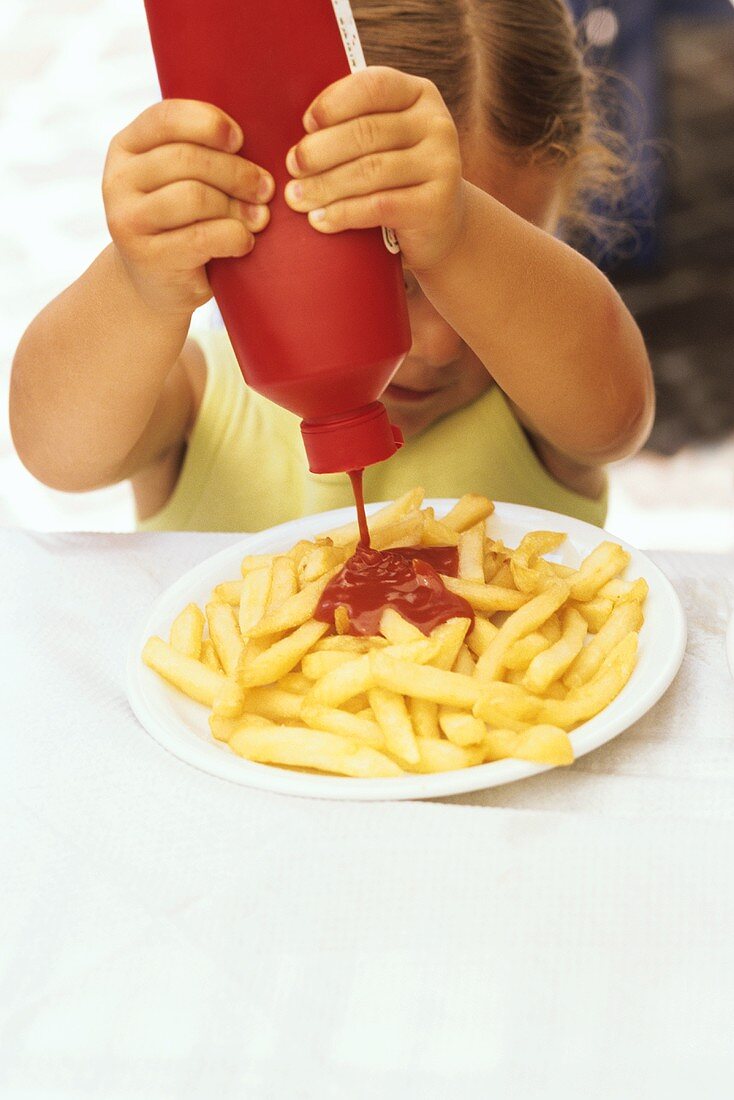 Girl squeezing ketchup over chips