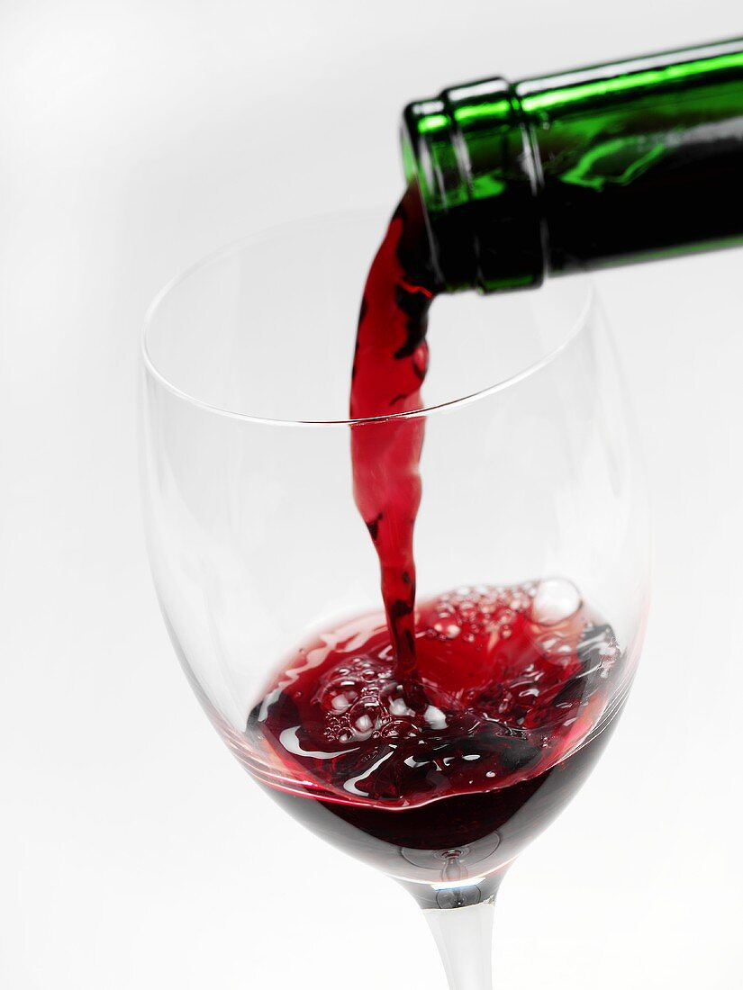 Rotwein wird in ein leeres Glas gegossen